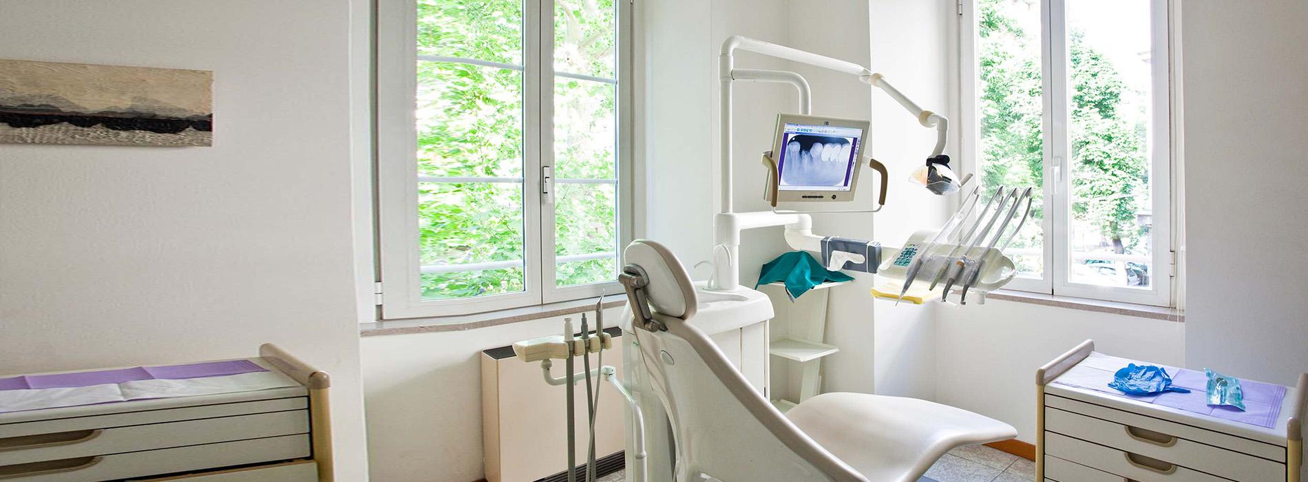 The image shows an interior space that appears to be a dental office, featuring a modern dental chair and equipment, with natural light coming through windows.