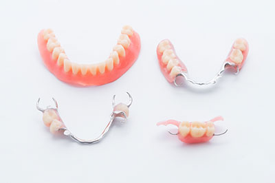 The image displays a set of dentures with visible teeth and gums, presented on a white background.