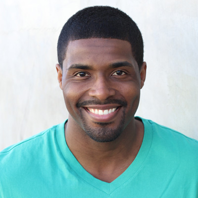 A man and a woman, both smiling, embracing each other in front of a scenic backdrop.