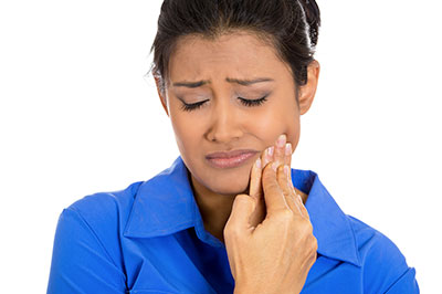 A woman with a concerned expression, holding her face and looking upwards.