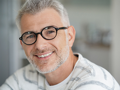 The image features a man with glasses and a beard, smiling at the camera.