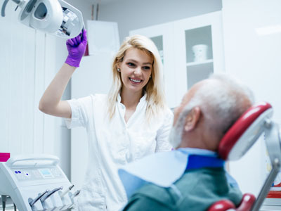 A dental professional is assisting an elderly patient during a medical procedure.