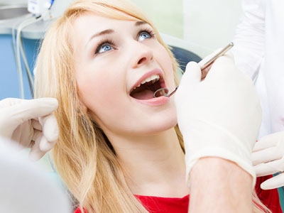 A woman in a dental chair receiving treatment, with a dental professional performing the procedure.