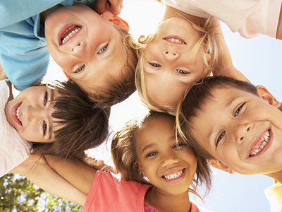 A group of children in a joyful pose, smiling and looking directly at the camera.