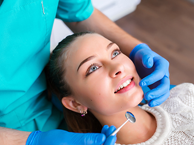 A dental professional performing a procedure on a patient s teeth, with the patient seated and smiling.